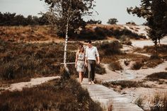 a man and woman walking down a wooden path