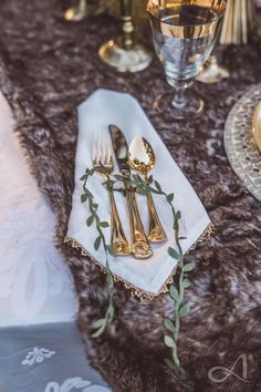 the table is set with silverware and gold utensils, along with napkins