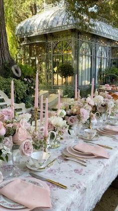 the table is set with pink and white flowers, gold place settings, and candles