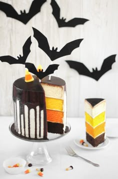 two cakes decorated with bats on top of a white table next to forks and spoons