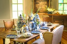 a dining room table with blue and white china on it's centerpieces