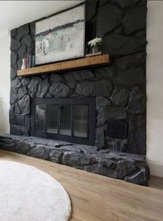 a living room with a large stone fireplace and white rugs on the hardwood floor