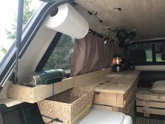 the interior of an rv with wood pallets and storage boxes on the bed area