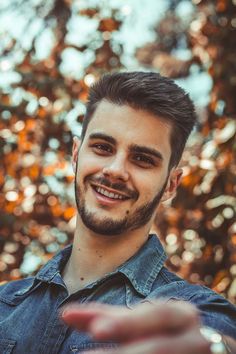 a man with a goatee smiles at the camera while holding his hand out in front of him