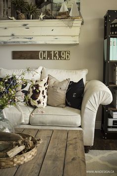 a living room filled with furniture and pillows on top of a wooden floor next to a window