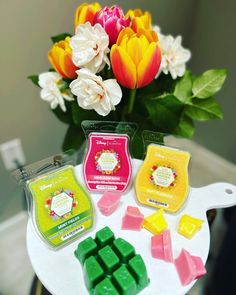 several wax cubes on a table with flowers in the background