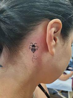 a woman with a bee tattoo on her left ear