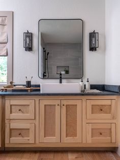 a bathroom with wooden cabinets and a large mirror above the sink in front of it