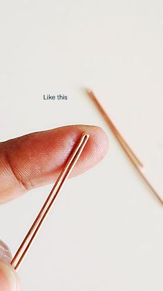 a hand holding a tiny metal needle with the tip pointing up to it's end