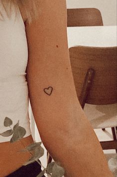 a woman with a small heart tattoo on her arm