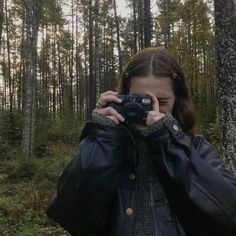 a woman taking a photo in the woods with her camera