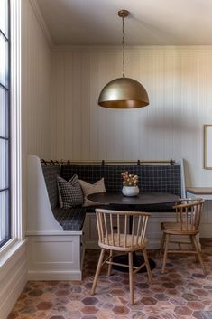 a dining room table with two chairs and a bench in front of the window next to it