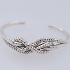 Get a close-up of the cleat knot with this intricate, adjustable bracelet. The Cleat Cuff bends slightly while retaining it's shape, so you can adjust as needed. The Cleat Cuff is available in three sizes. All three sizes are designed to bend to fit all wrists. The Large features a thick bracelet and big cleat, while the Small is much thinner and more bendable. Coming soon: Yellow and Rose Gold Cuffs! Adjustable Twisted Modern Jewelry, Modern Adjustable Twisted Jewelry, Adjustable Bangle With A Modern Twist, Adjustable Modern Twist Cuff Bangle Bracelet, Adjustable Sterling Silver Bracelet With A Modern Twist, Hitch Knot, Silver Bracelet Designs, Jewelry Hacks, Creative Shoes