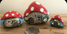 three painted rocks with houses on them next to a penny