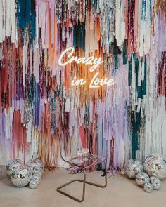 the neon sign is lit up in front of an abstract wall with colorful streamers