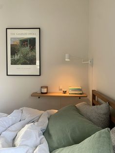 an unmade bed with green and white sheets in a bedroom next to a shelf