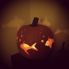 a carved pumpkin sitting on top of a wooden table next to a wall with lights