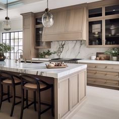 a large kitchen with marble counter tops and wooden cabinets, along with bar stools