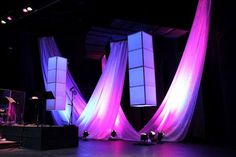 the stage is set up for an event with purple and white drapes on it