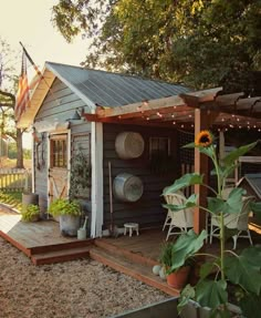 a small shed with pots and pans on the porch next to a sunflower