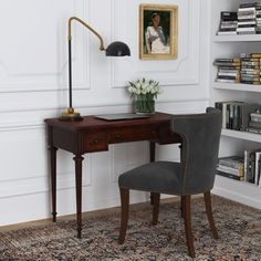 a desk with a chair, lamp and bookshelf in the corner next to it