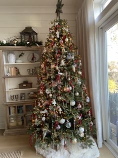 a decorated christmas tree in front of a window with lots of lights and ornaments on it