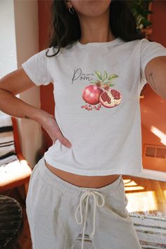 Introducing our irresistible Pomegranate Baby Tee, a delightful fusion of Y2K charm and vintage allure! Embrace nostalgia with this whimsical Fruit Crop Top that captures the essence of the '90s effortlessly. Crafted with care, this Coquette Shirt is designed to whisk you away to sun-soaked days and carefree moments. Its playful design adds a touch of retro flair to any ensemble, making it a must-have addition to your summer wardrobe. Elevate your style with our Summer Crop Top, perfect for thos White Graphic Tee With Fruit Print, Y2k Cotton T-shirt With Fruit Print, Relaxed Fit White T-shirt With Strawberry Print, Y2k T-shirt With Cherry Print, White Relaxed Fit T-shirt With Strawberry Print, Pomegranate Design, Fruit Shirt, 90s Tees, Graphic Crop Top