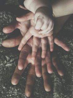 several hands are stacked on top of each other in the middle of a carpeted area