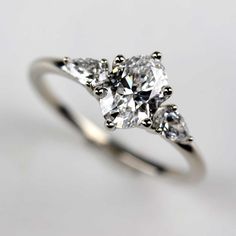 an engagement ring with three pear shaped diamonds on the sides and four prongs