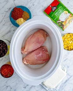 two raw chickens in a crock pot next to other ingredients