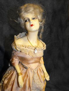 an old fashion doll wearing a brown dress