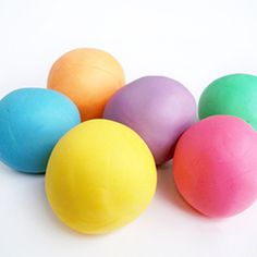 six balls of colored play dough on a white surface