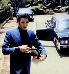 a man in a suit and tie standing next to a car