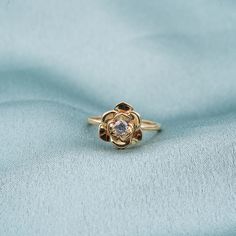 a gold ring with a diamond in the center on a blue cloth background, close up