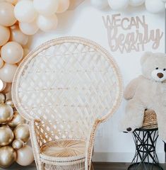 a white teddy bear sitting on top of a chair next to a wall with balloons