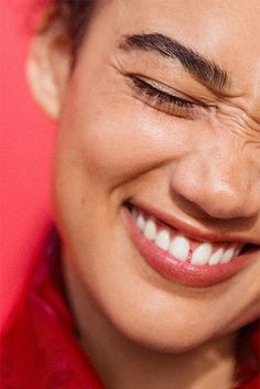 a smiling woman with her eyes closed wearing a red leather jacket and silver bracelets