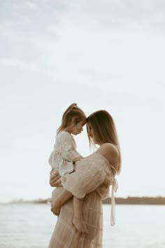 a woman holding a baby on the beach