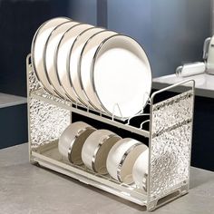 a silver dish rack with plates and cups in it