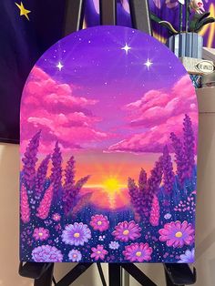 an easel painted with flowers and stars in the sky at sunset on a purple background