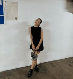 a woman standing in front of a white wall with her hand on her hip and smiling at the camera