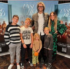 a group of people standing next to each other in front of a movie poster