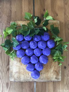 blue flowers are arranged in the shape of a heart on a cutting board with green leaves