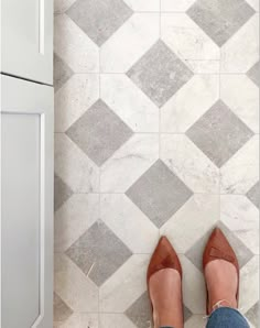 a woman's legs in high heels standing on a tiled floor