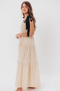 This dress is the perfect blend of femininity and contemporary comfort - meet the Amber Maxi Dress, a sweet and effortless gown for your next special event. We love its unique smocked bodice with a charming sweetheart neckline, plus self-tie shoulder straps in a sleek black hue. Pair this beauty with heels or slides and prepare yourself for the compliments! Available in two colorways. FIT: Runs true to size. Bodice is smocked and stretchy, but empire waist gives it a fitted structure that can be restricting for larger chests. Size up if you are between sizes. MATERIAL: GARMENT DETAILS: Lightweight maxi dress with empire-waisted silhouette and self-tie shoulder straps in contrasting color. Features a smocked bodice with sweetheart neckline, and a full, multi-tiered skirt. SIZE GUIDE: XS (0- Smocked Maxi Dress, Garment Details, Tiered Skirt, Empire Waist, Sweetheart Neckline, Special Event, Shoulder Straps, Contrasting Colors, Smocking