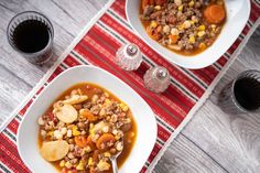 two bowls filled with soup on top of a red and white place mat next to silverware