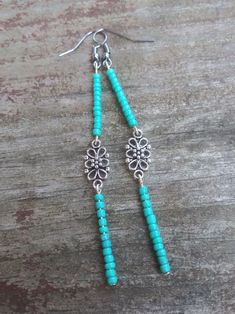 These beaded earrings feature a dark teal color and a flower connecter in the center. Elegant Turquoise Beaded Dangling Earrings, Artisan Turquoise Beaded Dangling Earrings, Turquoise Dangle Beaded Earrings For Gift, Turquoise Beaded Dangle Flower Earrings, Teal Beaded Earrings, Dark Teal Color, Teal Color, Native American Beading, Earring Tutorial