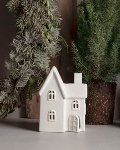 a small white house sitting on top of a table next to a potted plant