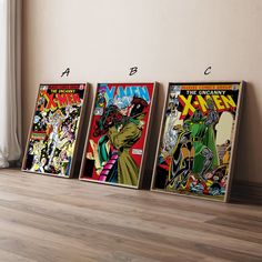 three framed comics are on the floor in front of a window and one has an image of comic book covers