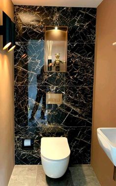 a bathroom with black marble walls and flooring, including a toilet in the middle