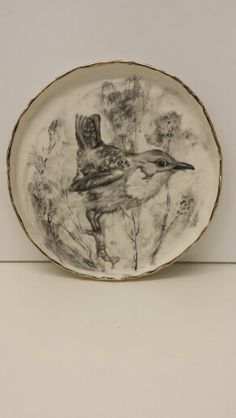 a plate with a bird on it sitting on top of a table next to a white wall